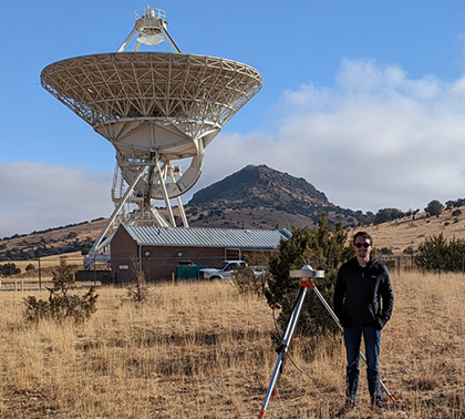 Graduate research assistant Joe Skeens stands in front of a GPS antenna deployed at the Very Long Baseline Array facility in Fort Davis, Texas.